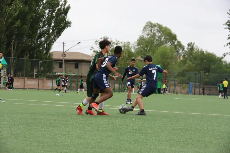 Beijing Huijia High School players competing for possession during a football match