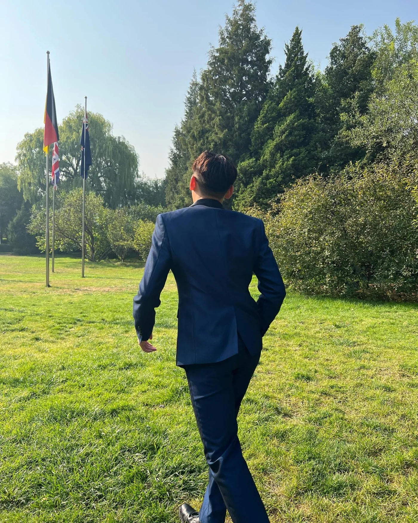 Kaize Zheng walking outdoors in a navy suit